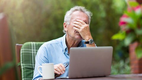 Mann unter Stress sitzt vor dem Laptop