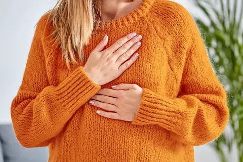 Junge, von Reflux geplagte Frau hält Hand auf Speiseröhre