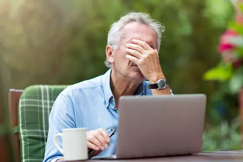 Mann unter Stress sitzt vor dem Laptop