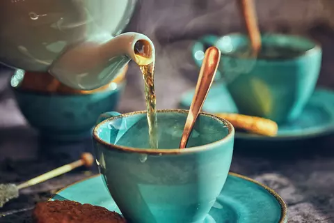 Tee wird in Tasse eingeschenkt