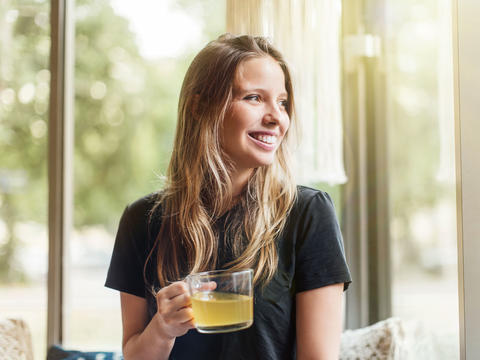 Lachende Frau mit Tee-Glas in der Hand