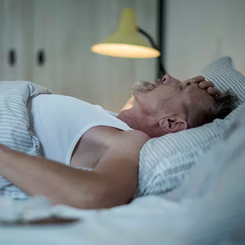 Von Sodbrennen geplagter Mann liegt nachts wach im Bett